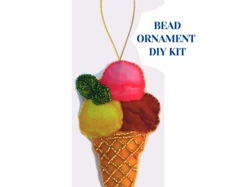 May include: A handmade ice cream cone ornament with three scoops in pink, brown, and yellow, topped with green beaded leaves. The cone is orange with gold beaded details, and the ornament has a gold string for hanging. Text reads: BEAD ORNAMENT DIY KIT.