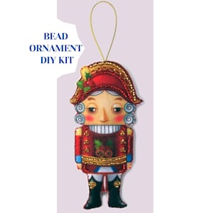 May include: A decorative bead ornament DIY kit in the shape of a nutcracker soldier. The ornament features a red hat and jacket with gold accents, a white face, and black boots. The text "BEAD ORNAMENT DIY KIT" is printed on the upper left.