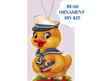 May include: A yellow duckling bead ornament DIY kit. The duckling wears a sailor hat and scarf with blue and white accents. The duckling is holding a small boat. The text "BEAD ORNAMENT DIY KIT" is in the upper right corner.