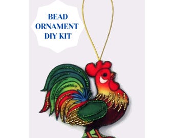May include: A colorful rooster bead ornament DIY kit. The rooster has a red comb, a green and red tail, and gold bead accents. The ornament hangs from a gold string. Text on the image reads: BEAD ORNAMENT DIY KIT.