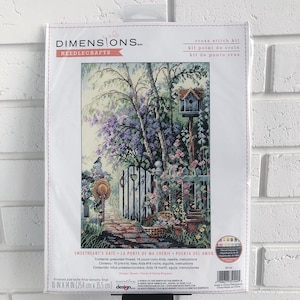 May include: Cross stitch kit featuring a colorful scene of a gate with a birdhouse and flowers. The kit includes presorted thread, 14 count ivory Aida, needle, and instructions. The finished size is 10 inches by 14 inches.