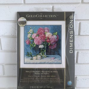 Puede incluir: Un kit de punto de cruz con un ramo de flores rosas y blancas en un jarrón de vidrio. El kit se titula "Mary's Bouquet" y está diseñado por Robin Anderson. El kit mide 30,4 cm por 30,4 cm.