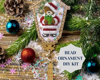 May include: A wooden bead ornament kit featuring a Christmas lantern design with a bear inside. The kit includes beads, thread, and instructions.  "Bead Ornament DIY Kit" is written on a blue and white label.