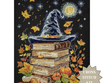May include: A cross-stitch kit featuring a witch's hat atop a stack of books, surrounded by pumpkins and autumn leaves. The background is a starry night with a full moon. The words "CROSS STITCH KIT" are in a starburst.