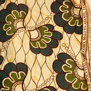 May include: A white fabric with a brown and green floral pattern. The fabric has a brown border with the text "LTD. POLYTEX MOROGORO. MALI YA ASANTE TANZANIA" printed on it.