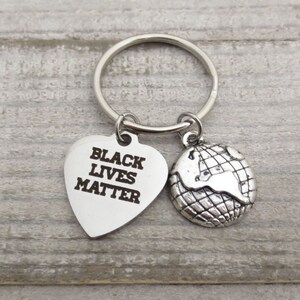 May include: Silver keychain with a heart-shaped charm that says "Black Lives Matter" and a globe charm.