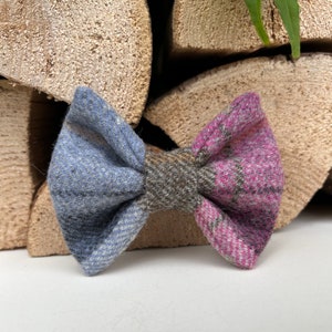 May include: A blue, brown, and pink plaid bow tie. The bow tie is made of a soft, textured fabric.