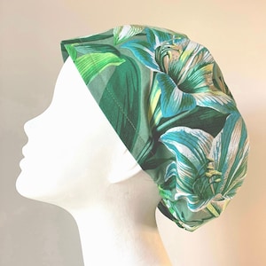 Peut inclure: Un bonnet de travail floral vert et blanc avec un motif de lys blanc.