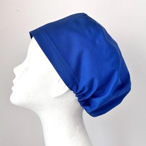 May include: A royal blue scrub cap with a gathered back. The cap is made of a soft, comfortable fabric and is perfect for keeping hair out of the way while working.