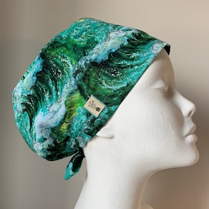May include: Green and blue patterned surgical scrub hat with a white label. The pattern features a wave design.