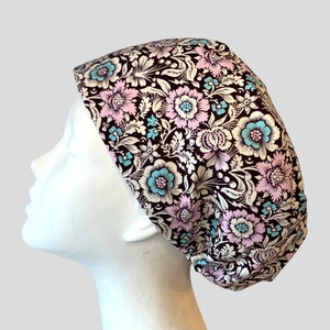 May include: A brown scrub hat with a floral pattern featuring pink, white, and blue flowers. The hat is made of a soft, comfortable fabric and is perfect for nurses, doctors, and other healthcare professionals.