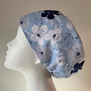 May include: A light blue scrub hat with a white and navy blue floral pattern.