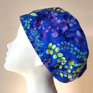 May include: A blue scrub hat with a floral pattern featuring green, purple, and white flowers on a blue background.