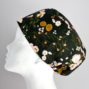 May include: A dark green scrub hat with a floral print featuring pink and yellow flowers. The hat has a gathered elastic band at the back.