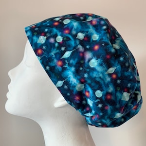 May include: A blue scrub hat with a pattern of white and red orbs on a dark blue background.