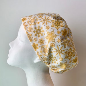 May include: White scrub cap with a gold snowflake pattern.