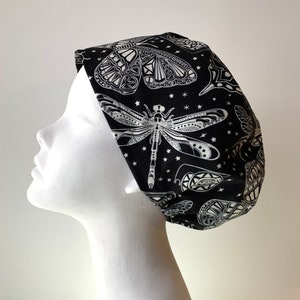 Peut inclure: Un bonnet de travail noir avec un motif de libellule et de papillon blanc. Le bonnet a un motif d'étoiles blanches sur fond noir.