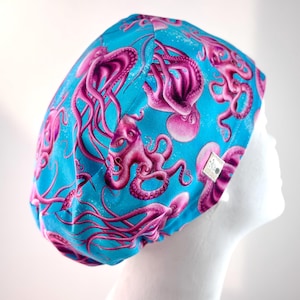May include: A blue and pink surgical scrub hat with a pattern of pink octopuses on a blue background.