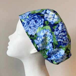 May include: A blue and green patterned scrub hat with a floral design featuring hydrangeas.