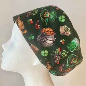 May include: Green scrub hat with a repeating pattern of shamrocks, leprechaun hats, pots of gold, pipes, and beer mugs.