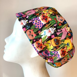 May include: A colourful surgical scrub hat featuring a pattern of cats and flowers. The hat is made from a soft, comfortable fabric and is ideal for nurses, doctors, and other healthcare professionals.