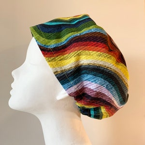 May include: A colourful striped scrub hat with a wavy pattern in shades of blue, green, yellow, orange, and red.