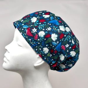 May include: A dark teal scrub cap with a festive pattern featuring red birds, white clouds, stars, and green foliage. The cap is designed to fit comfortably and securely, offering a stylish and functional accessory for medical professionals.