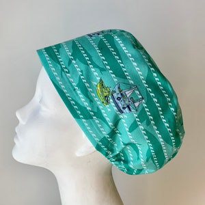 May include: A turquoise blue surgical scrub hat with a white pattern of repeating waves and a small sailboat.