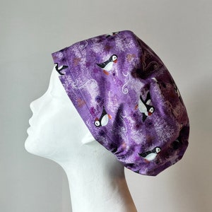 May include: Purple scrub hat with a white background and a repeating pattern of black and white puffins.