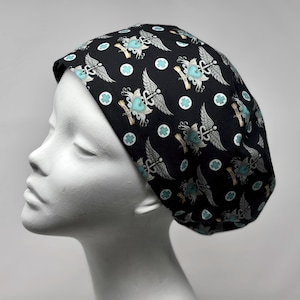 Peut inclure: Bonnet de chirurgien noir avec un motif répété de cœurs ailés, de symboles de caducée et de croix turquoise. Le motif comprend des bannières enroulées. Le bonnet est en tissu souple.