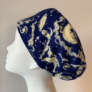 May include: A blue scrub hat with a white celestial pattern. The pattern includes stars, planets, and other celestial bodies.