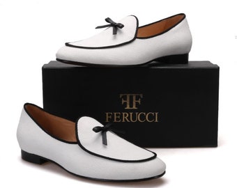 May include: White canvas loafers with a black trim and a black bow on the top. The shoes are on a black box with the text "FF Ferrucci" in gold.