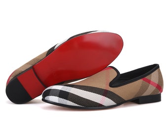 May include: A pair of brown, black, and white plaid slip-on shoes with red soles.