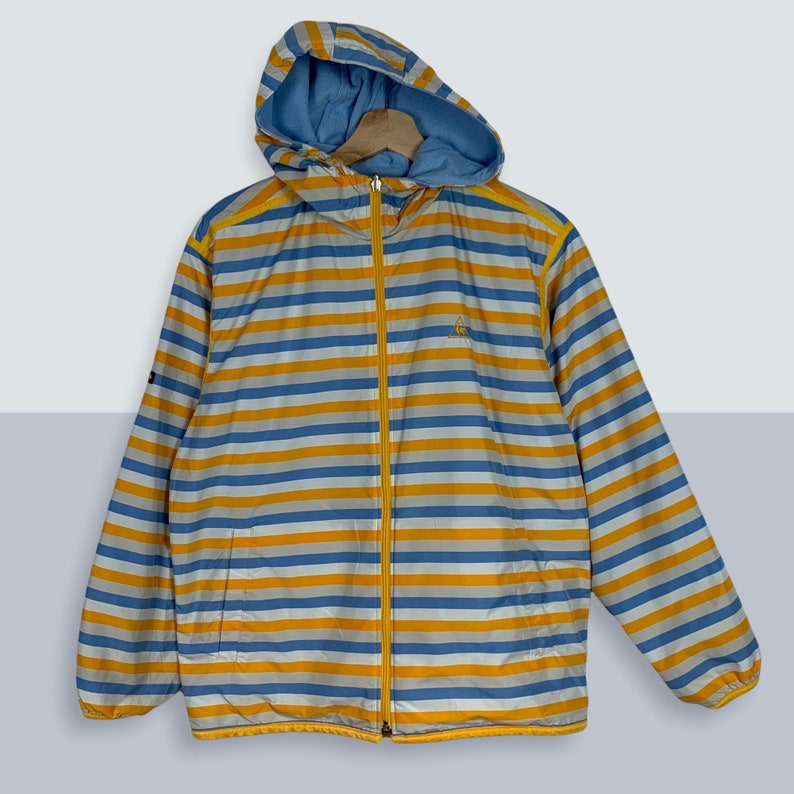 May include: A blue and yellow striped hooded jacket with a zipper closure. The jacket has a small logo on the left chest.