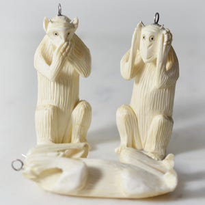 May include: Three ivory carvings of monkeys, each representing a different part of the saying "See no evil, hear no evil, speak no evil". The monkey on the left is covering its mouth, the monkey in the middle is covering its ears, and the monkey on the right is covering its eyes.