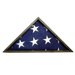 May include: A wooden triangular shadow box with a folded American flag inside. The flag is blue with white stars.