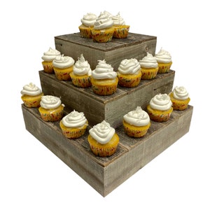May include: A three-tiered wooden cupcake stand with a rustic finish. The stand is filled with yellow cupcakes topped with white frosting and sprinkles.