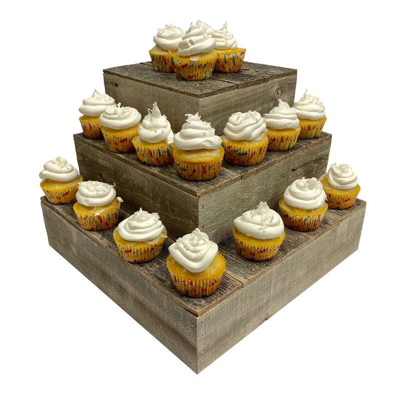May include: A three-tiered wooden cupcake stand with a rustic finish. The stand is filled with yellow cupcakes topped with white frosting and sprinkles.