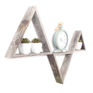 May include: A set of three triangular wooden shelves in a gray wash finish. The shelves are arranged in a V shape and feature a small clock and two potted plants.