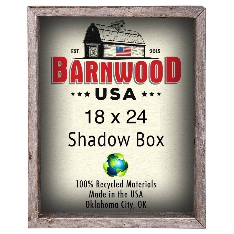 May include: A rustic wooden shadow box frame with a white background and red, white, and blue barnwood logo. The logo reads "Barnwood USA" and "18 x 24 Shadow Box". The frame is made from 100% recycled materials and is made in the USA.
