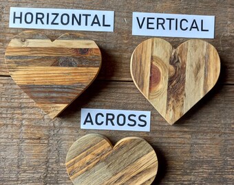 May include: Three wooden heart-shaped decorations with varying wood grain patterns. The hearts are arranged with the words "HORIZONTAL", "VERTICAL", and "ACROSS" on white labels. The background is a rustic wooden surface.