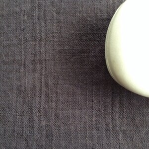 May include: A close-up of a dark gray fabric with a subtle woven texture.