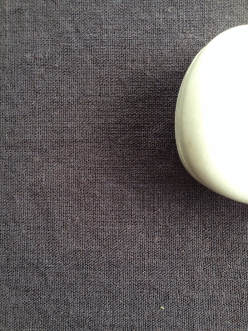May include: A close-up of a dark gray fabric with a subtle woven texture.
