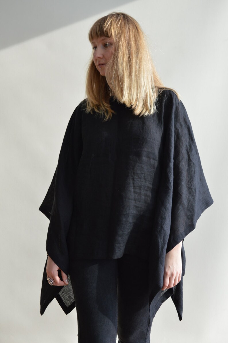 May include: A black linen poncho with a loose, flowing fit. The poncho is worn over black pants.