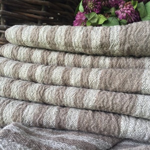 May include: A stack of six brown and white linen tea towels with a woven pattern. The towels are folded and stacked on top of each other.