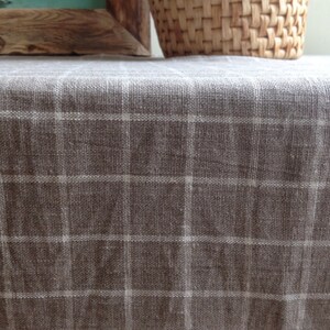 May include: A brown linen tablecloth with a white checkered pattern. The tablecloth is smooth and has a subtle sheen.