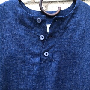 Op de afbeelding: Een donkerblauw linnen shirt met een v-hals en drie knopen.