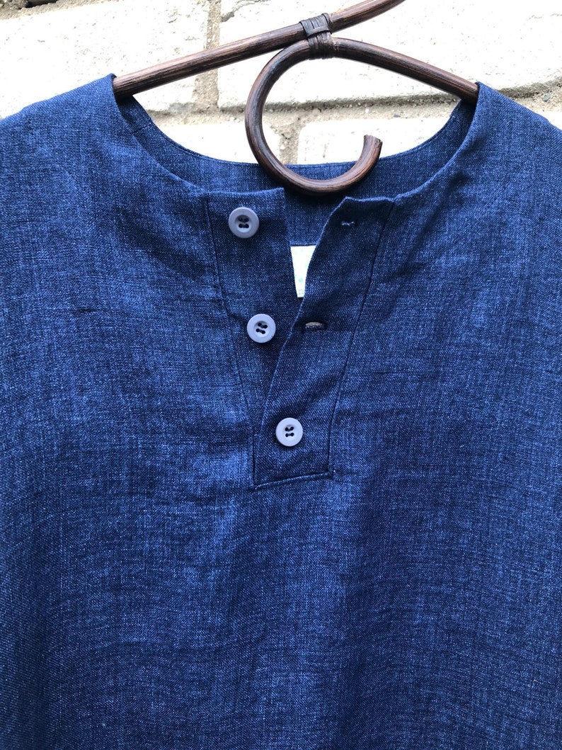 Op de afbeelding: Een donkerblauw linnen shirt met een v-hals en drie knopen.