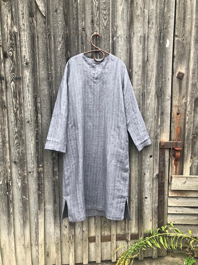 Op de afbeelding: Een grijs linnen shirt met witte strepen en een knoopsluiting aan de voorkant. Het shirt heeft lange mouwen en zijsplitten.