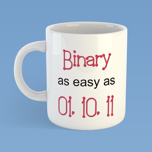 May include: White ceramic mug with a curved handle. The mug features the text "Binary as easy as 01. 10. 11" in red and black. The mug is set against a light blue background.